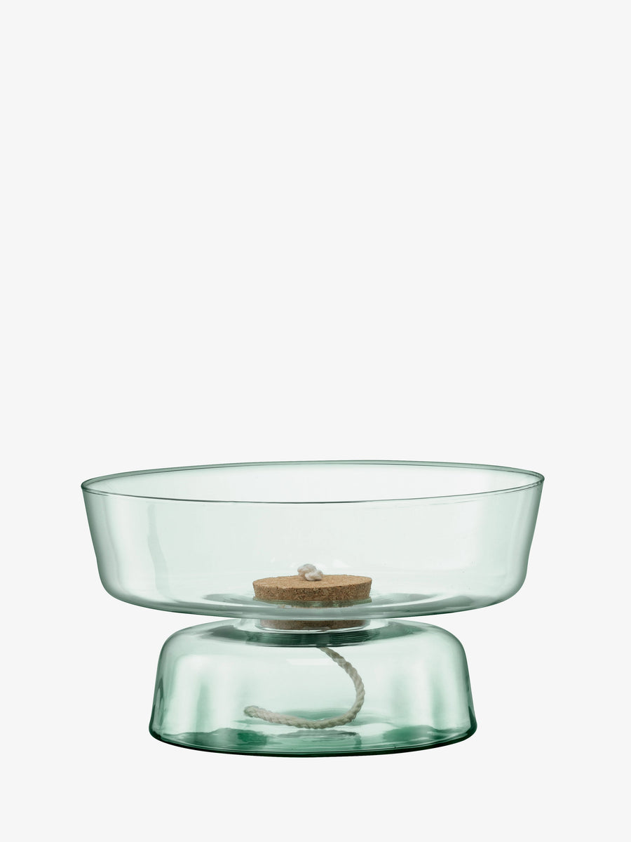 The lsa-international Self Watering Planter, crafted from clear recycled glass with a wide bowl shape and finished with a cork stopper and central white wick, evokes elegant simplicity against a plain white background.