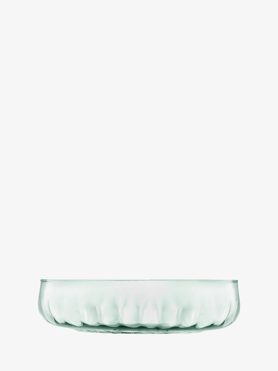 A transparent, round Low Bowl by lsa-international is placed on a white background. Handmade with a fluted edge, the bowl is empty and viewed from the side, showcasing its clear, simple design and elegant fluted texture along with a subtle reflection at the base.