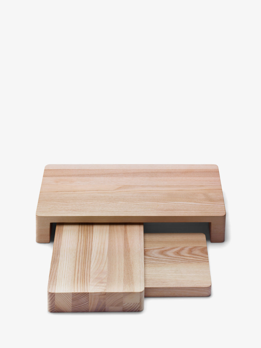 The Ash Wood Platter Set by lsa-international features three rectangular cutting boards crafted from light-colored ash wood, cleverly stacked in a modular serving design. The largest board sits on top with a recessed space below, where two smaller boards are partially pulled out. The set is displayed against a white background.