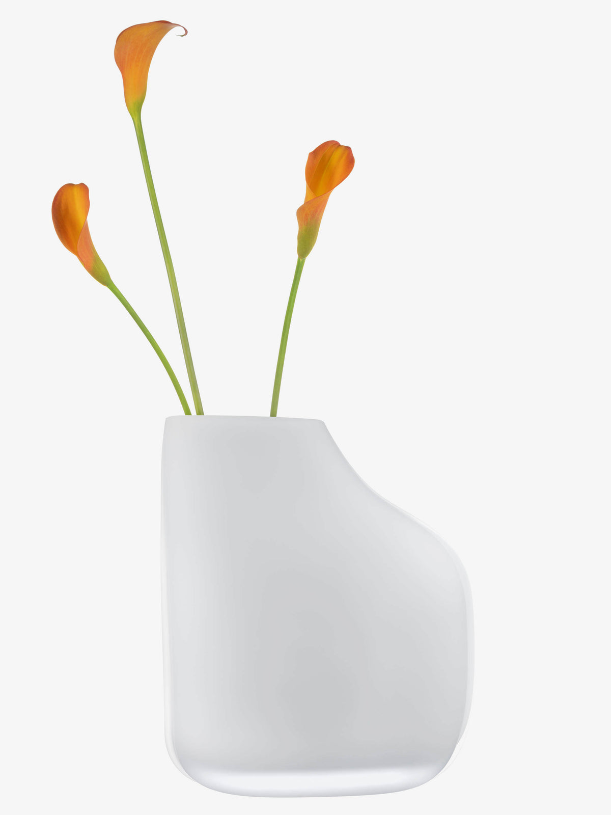 The lsa-international 1966 Vase, featuring a modern white asymmetrical design, is displayed with three orange calla lilies with long green stems against a plain white background.