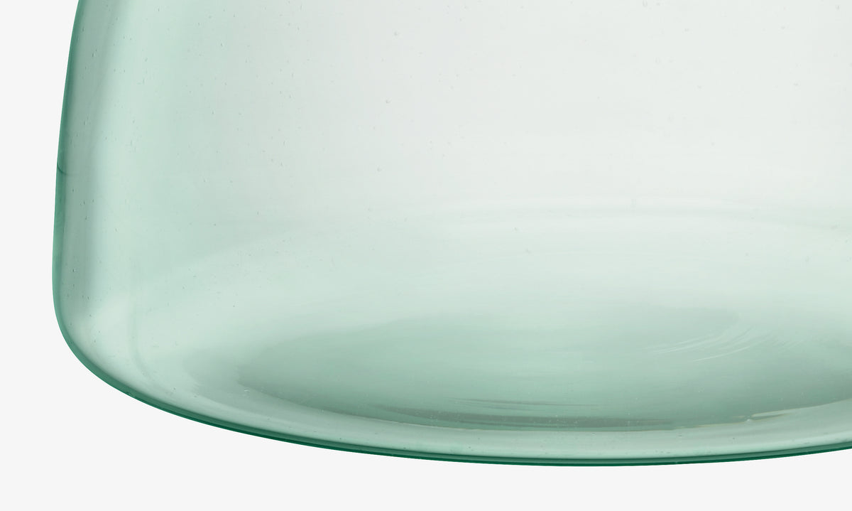 Close-up of a translucent, light green glass object with a smooth surface and curved edge, likely the bottom portion of the Closed Garden sustainable planter by lsa-international.
