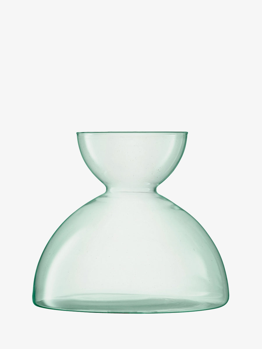 A transparent, light green lsa-international Vase featuring a wide, rounded base and a smaller, bowl-shaped top is photographed against a white background.