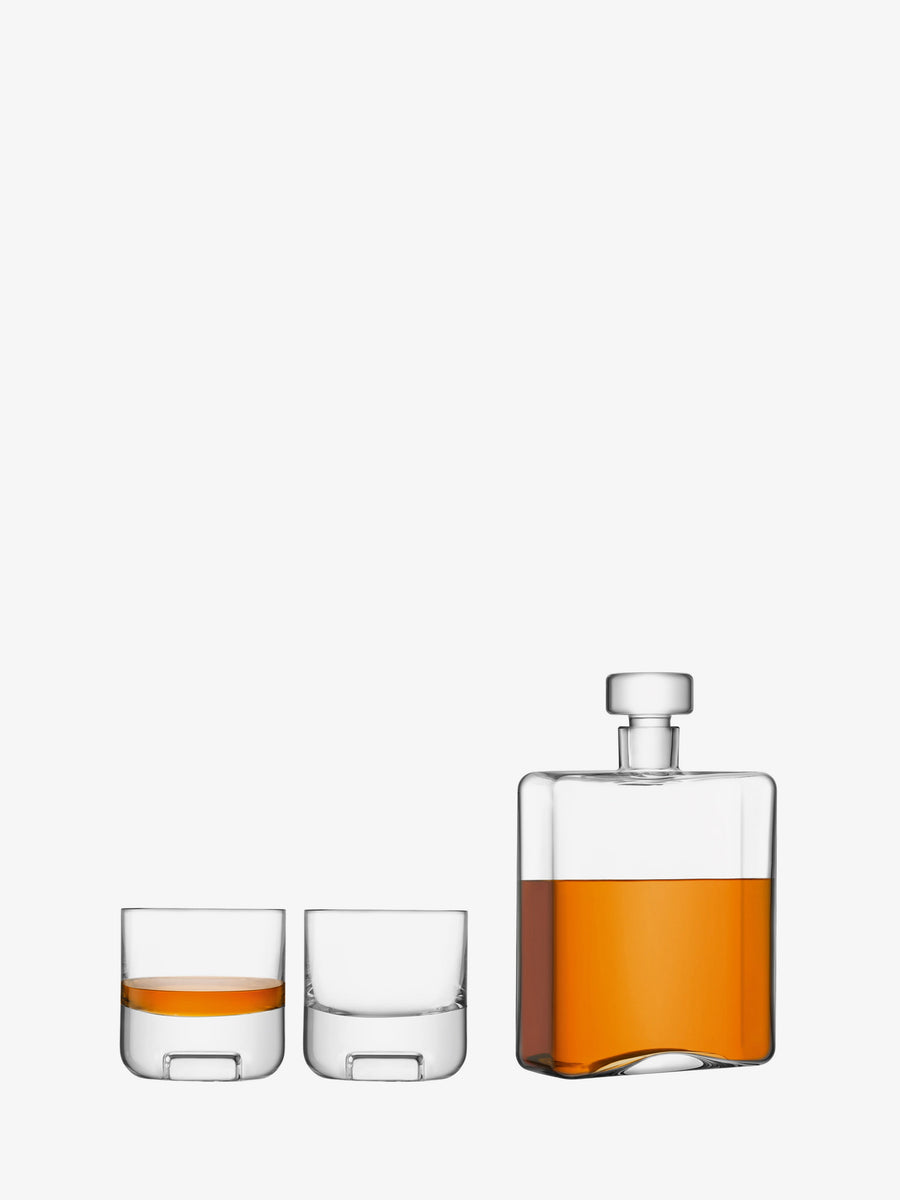 A mouth-blown decanter filled with amber liquid stands next to two short glass tumblers, one empty and one partially filled, all on a white background—a refined Whisky Set Clear by lsa-international, perfect for any connoisseur.