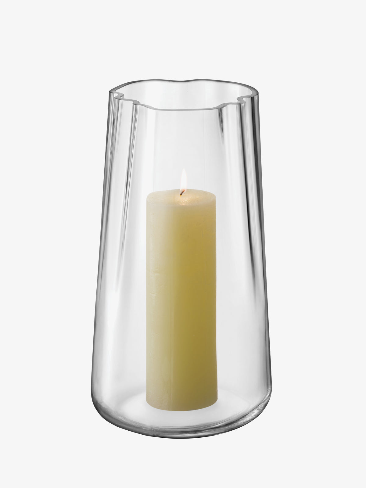 An LSA International Vase/Lantern with an organic form and a scalloped rim containing a lit cream pillar candle.