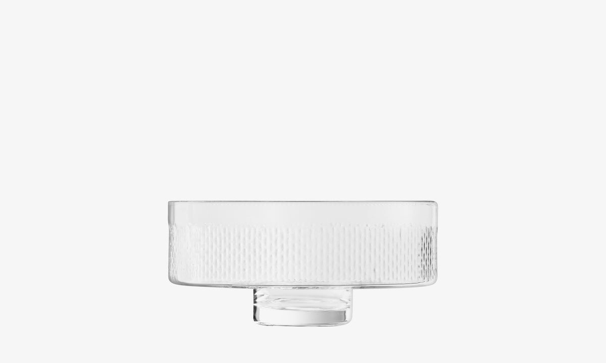 The lsa-international Comport is a clear, cylindrical glass bowl featuring a textured vertical line pattern. Mouth-blown for quality, it sits elegantly atop a short, round pillar stem pedestal base and is showcased against a plain white background.