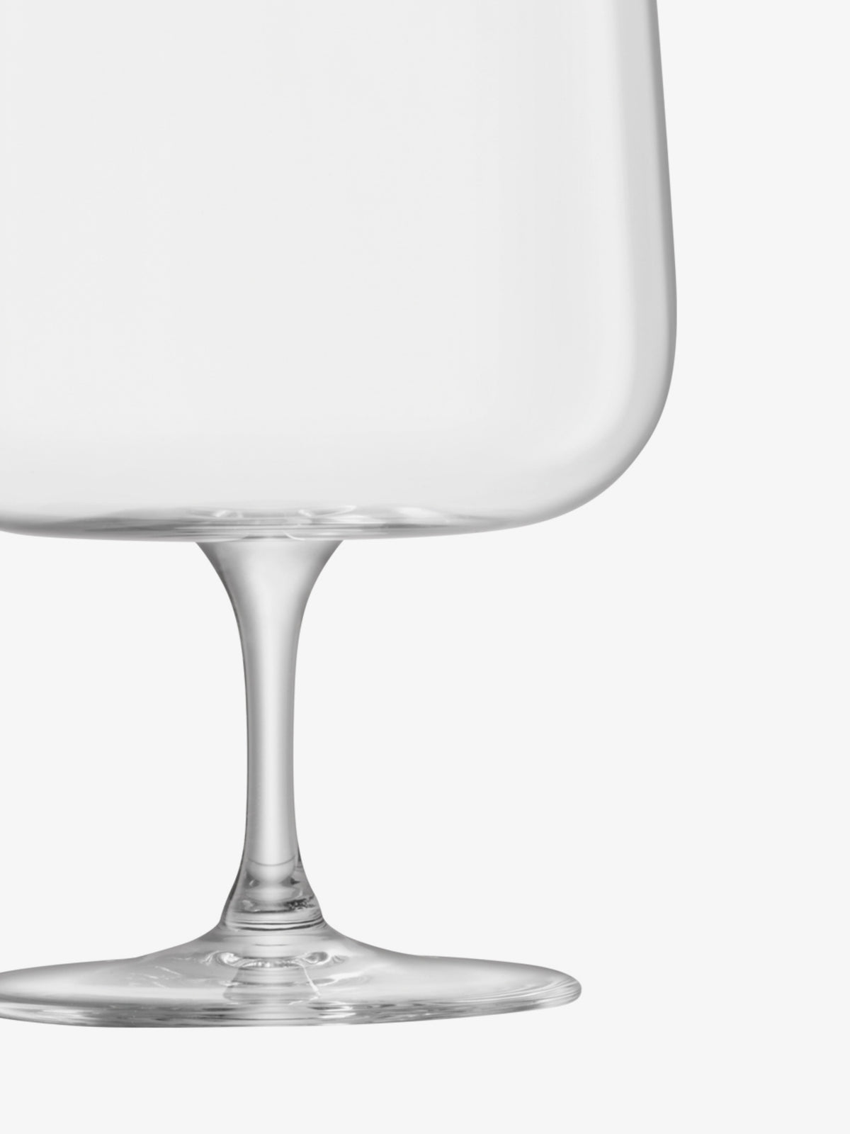 A close-up of the lower half of a clear wine glass, showing the stem and base against a white background.