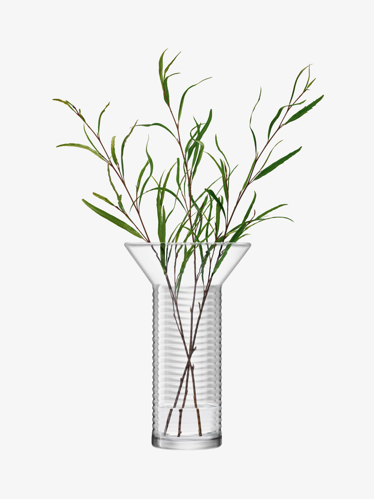 Tall, mouth-blown LSA-International Vase with a flared top and ribbed cylindrical base, containing several thin, leafy green stems.