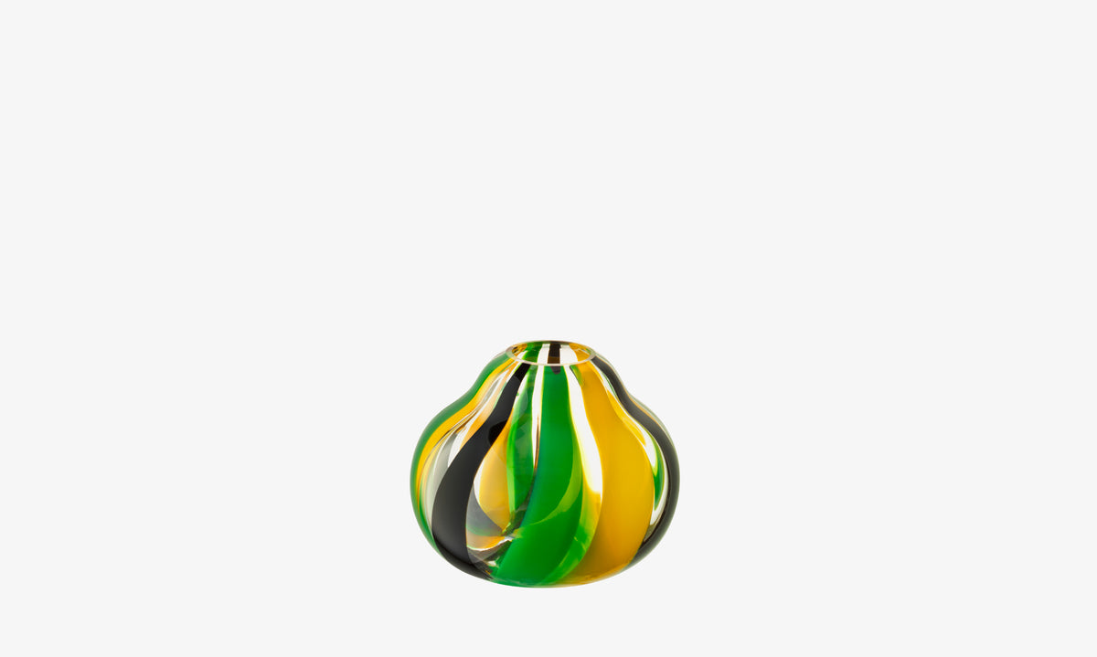 The Vase by lsa-international is a small round mouth-blown piece featuring swirling yellow, green, and black stripes—an eye-catching folk-inspired table centrepiece on white.