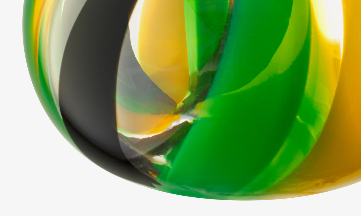 Close-up of the lsa-international Vase, mouth-blown with swirling green, yellow, black, and clear sections, creating an abstract colourful pattern—ideal as a striking table centrepiece.