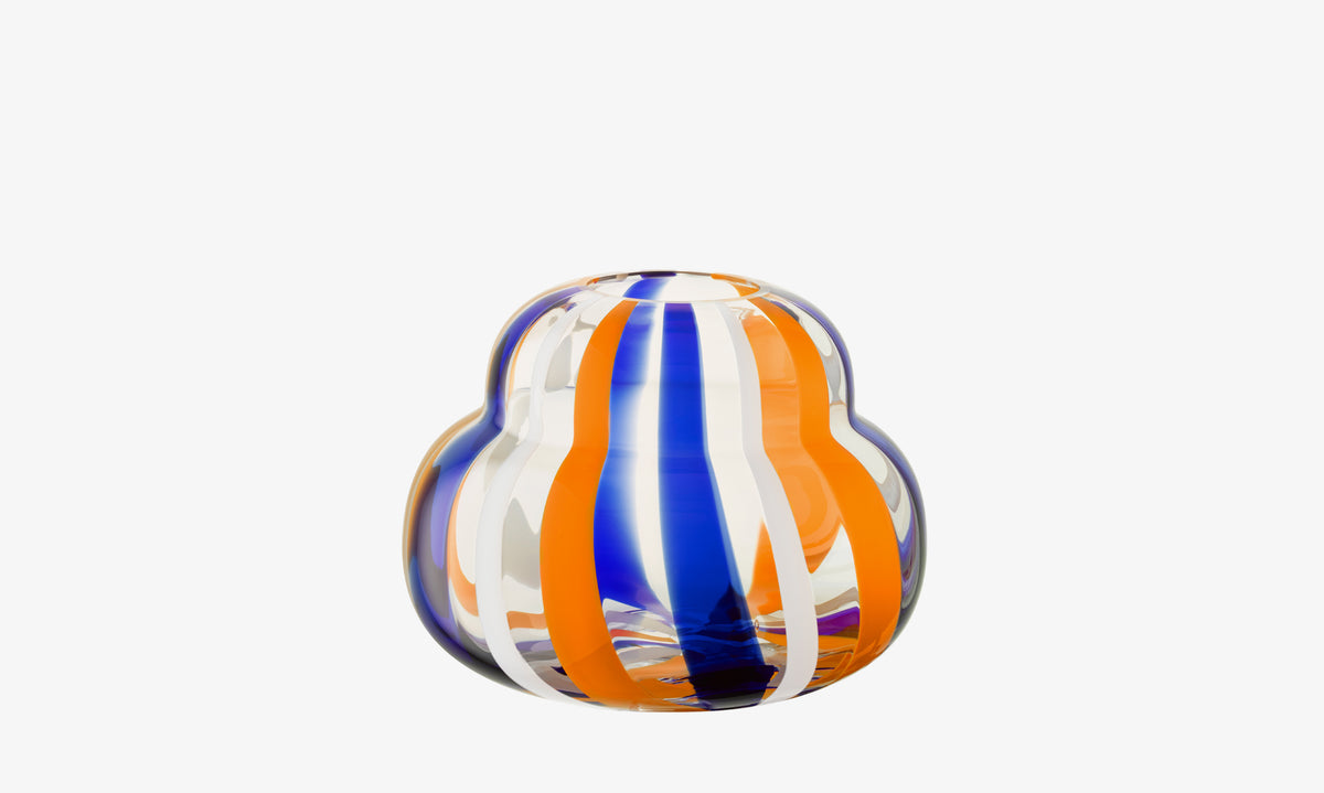 The Vase by lsa-international is mouth-blown with bulbous curves and features vertical orange, blue, and white stripes, set against a plain white background.