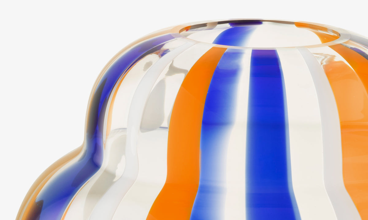Close-up of the lsa-international Vase, featuring mouth-blown glass with vertical orange, blue, and white stripes, a rounded curved shape, and a glossy reflective finish.