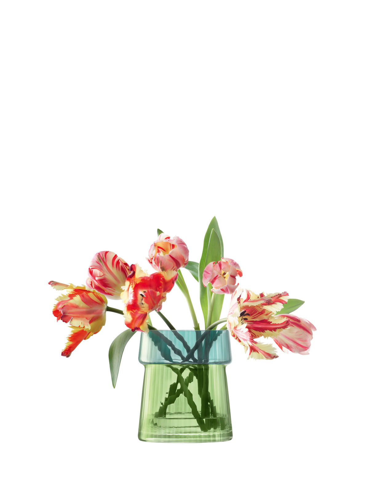 A charming arrangement of pink and yellow tulips with lush green leaves is elegantly displayed in the lsa-international Vase/Lantern, a mouth-blown glass piece featuring a delicate pleated texture, set against a white background.