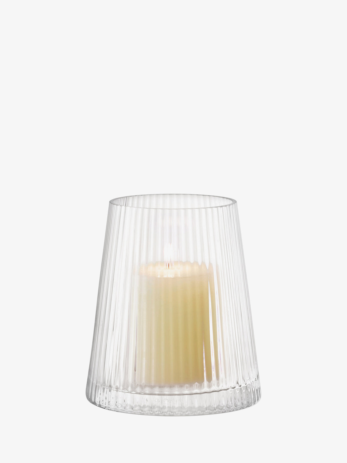 A lit pillar candle sits inside an LSA International Lantern/Vase, a mouth-blown glass vessel with a fluted, pleated design.
