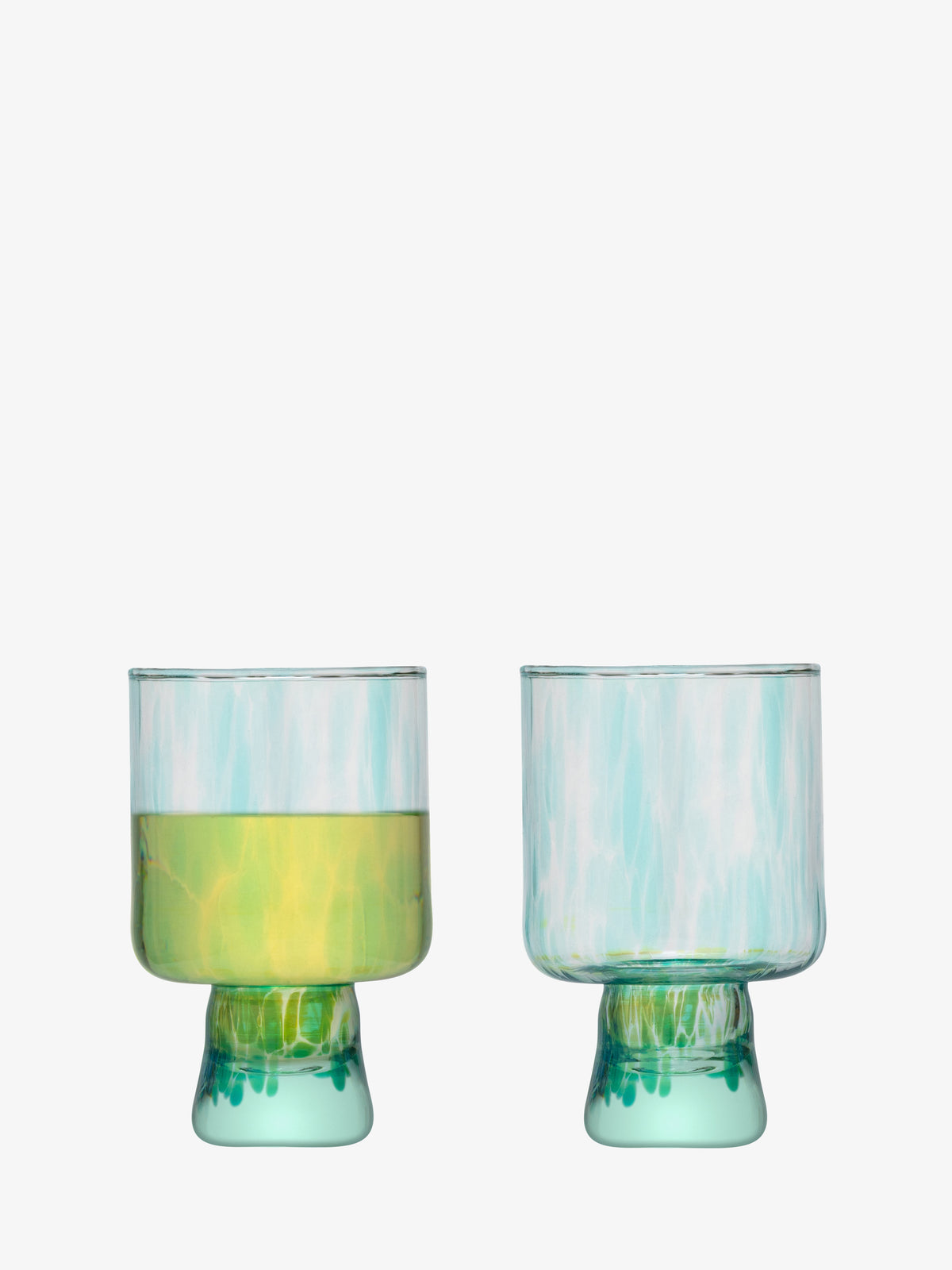 Two lsa-international Wine Glasses with thick stems and greenish-blue bases, crafted from recycled glass. The left glass holds a yellow liquid while the right is empty; both feature a short, wide shape with a translucent, slightly textured finish and a subtle speckled pattern.