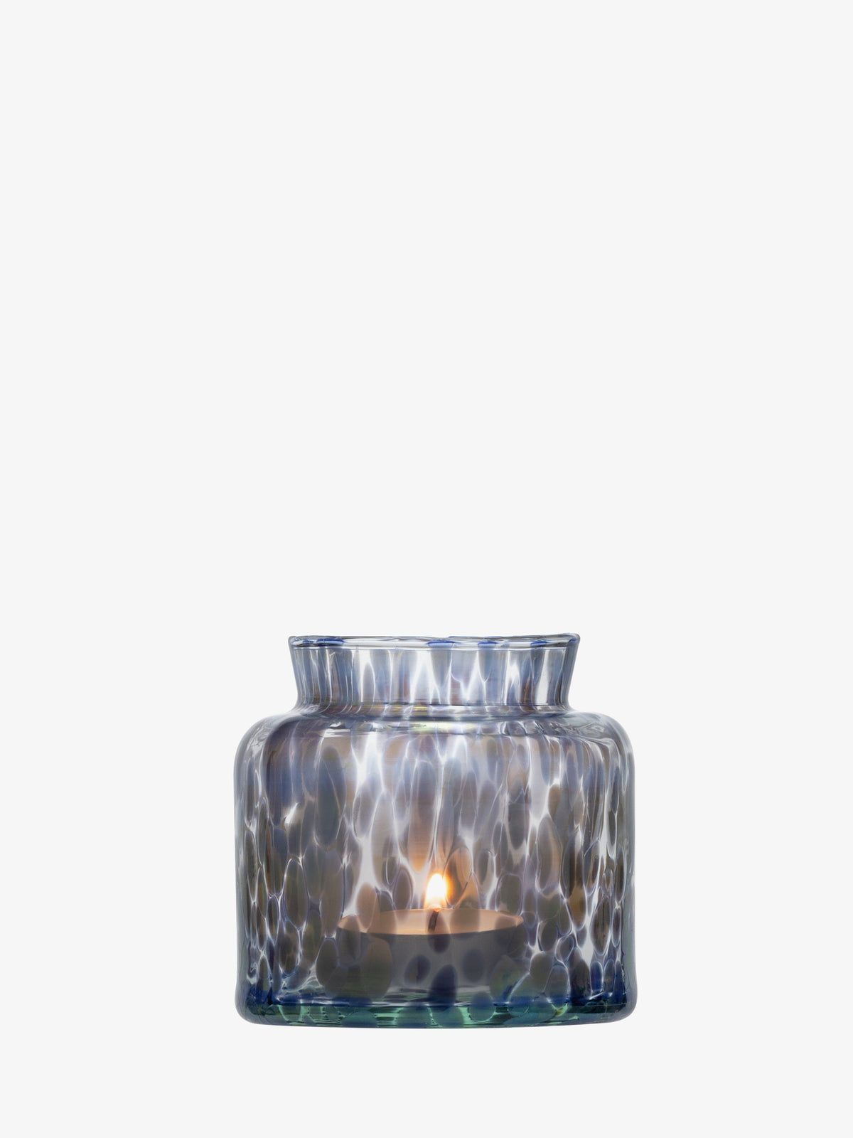 A lit tealight candle sits inside the lsa-international Tealight Holder/Vase, crafted from translucent, blue-speckled recycled glass, set against a white background. The holder beautifully reflects the candlelight, casting soft, glowing patterns.