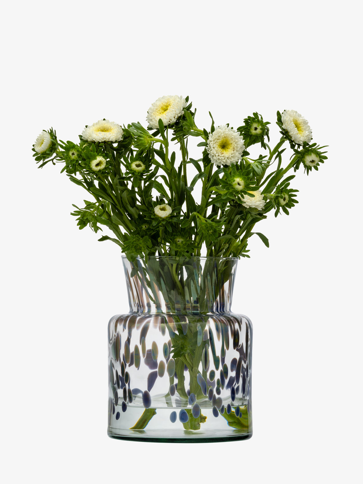 A bouquet of white flowers with green stems is displayed in the lsa-international Vase/Lantern, a mouth-blown glass piece adorned with blue and green spots, set against a plain white background.
