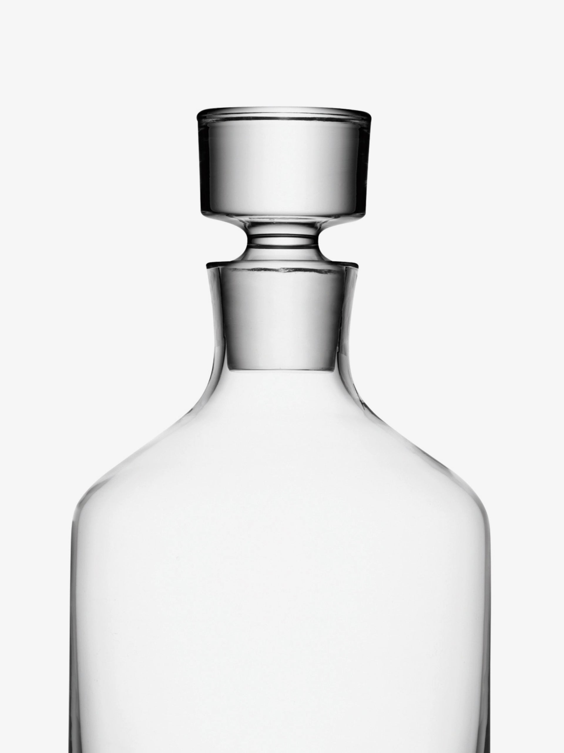 A clear glass decanter with a wide, round stopper sits against a plain white background. The simple, elegant design highlights the transparency and smooth curves of the glass.