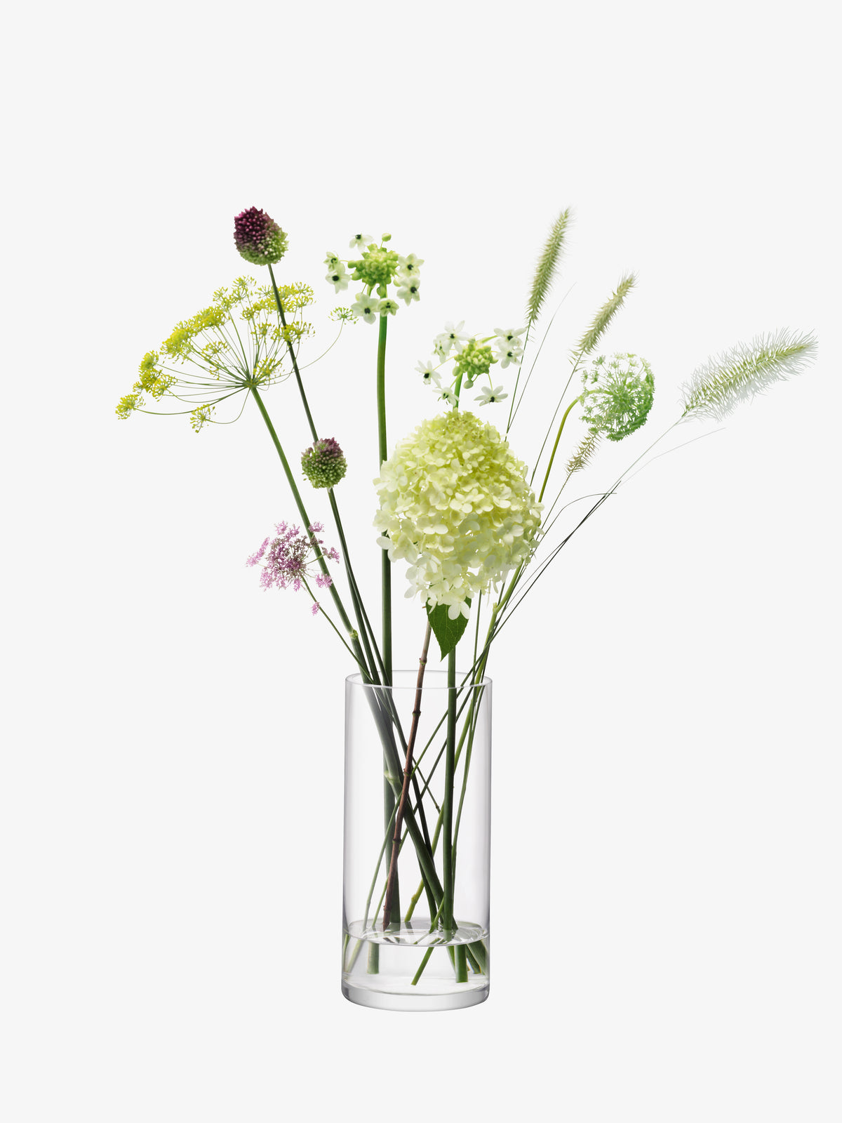 An LSA International cylindrical glass vase containing a bouquet of green hydrangeas, wild grasses, and various small wildflowers.
