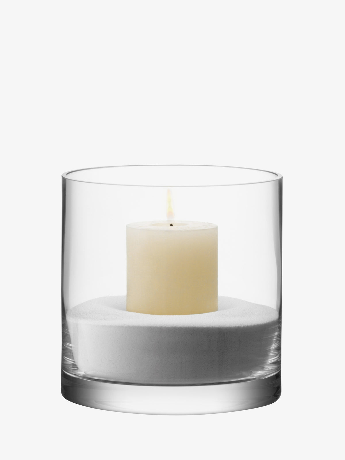 An LSA International Vase/Candleholder featuring a clear, mouth-blown glass cylinder lantern containing a white pillar candle resting in a bed of white sand.