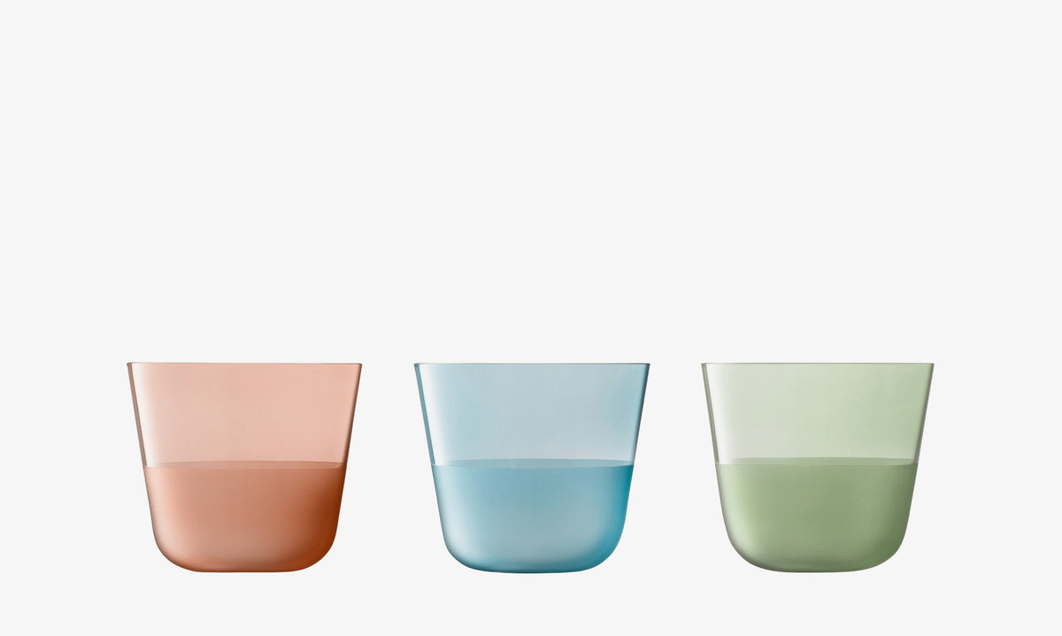 Six translucent low tumblers from the lsa-international Colour Tumbler Bundle - Low (6 piece) set, each in vibrant shades of pink, blue, and green and half-filled with matching colored liquid, are arranged in a row against a plain white background—an elegant display of coloured glassware.