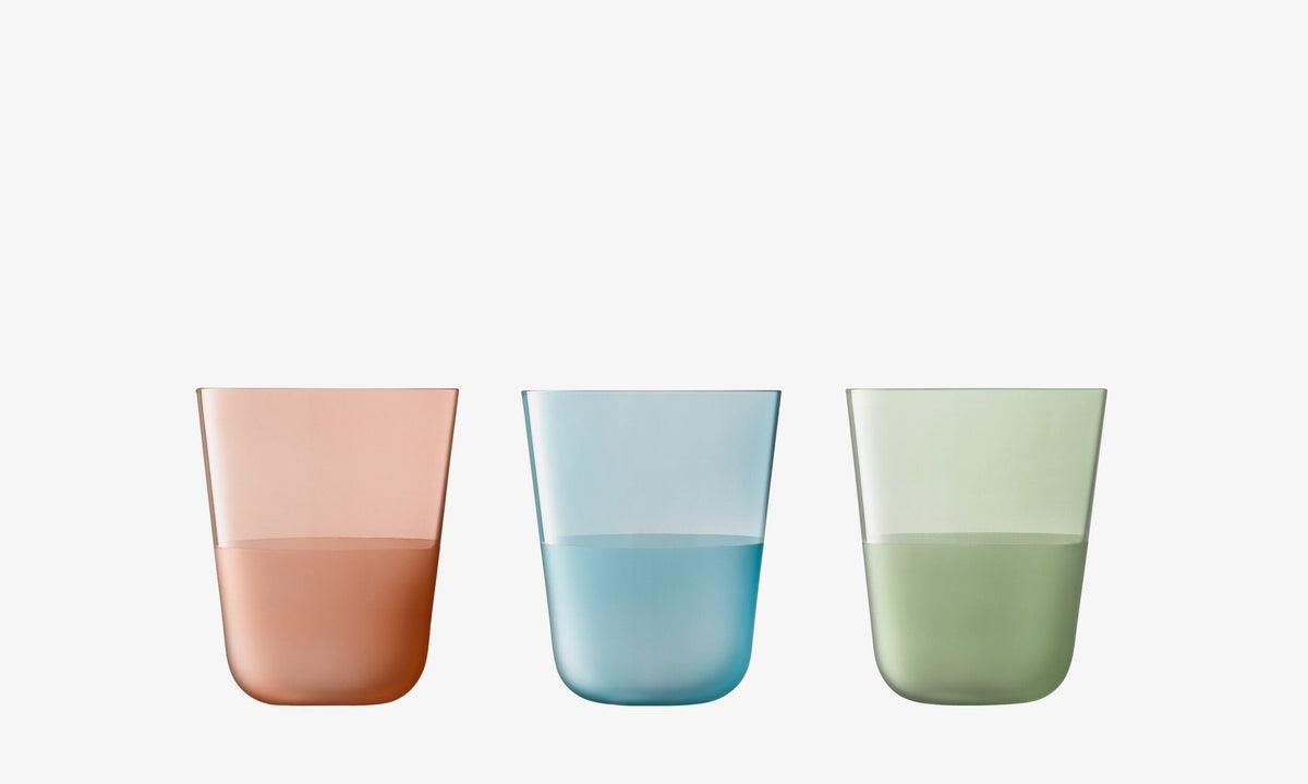 Three transparent tall tumblers from the lsa-international Colour Tumbler Bundle - Tall (6 Piece) set, each half-filled with liquid; the left tumbler is pink, the middle is blue, and the right is green. Each glass showcases a matte textured finish from the signature Arc Contrast collection and is displayed against a plain white background.
