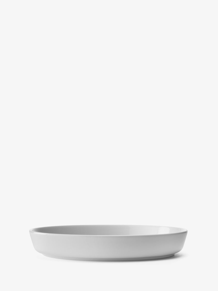 A minimalist, empty white ceramic serving bowl by lsa-international, crafted from vitrified porcelain, is centered on a white background and viewed from a low side angle.