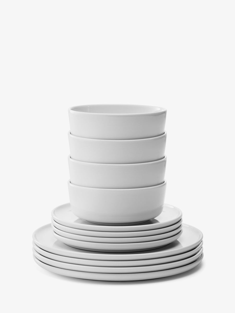 A set of four white bowls is stacked on top of six dinner plates, all from the lsa-international 12 Piece Set, arranged neatly against a white background—an elegant porcelain collection that combines style with dishwasher-safe convenience.